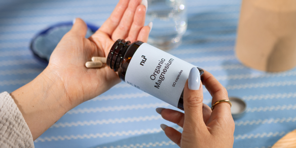 Magnesium Dose und zwei Kapseln in einer Hand