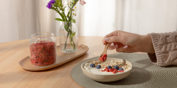 Frau streut Goji Beeren über ihr Müsli