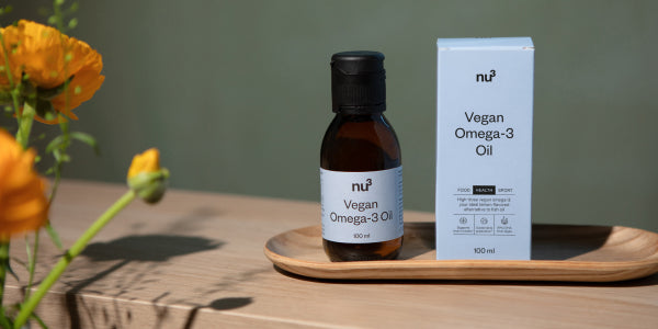 vegan omega-3 Öl Fläschchen und Verpackung auf Holztablett