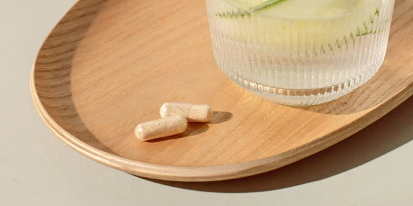 Vitamin C Kapseln mit Glas Wasser