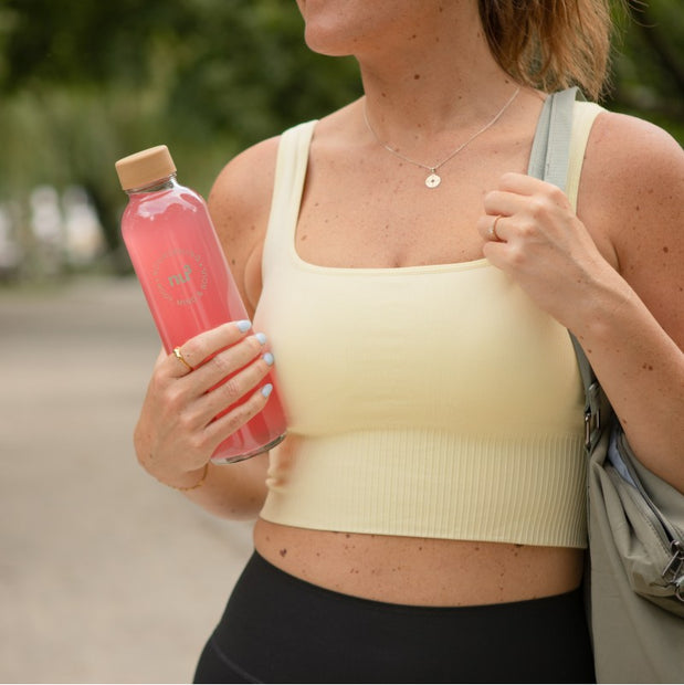Sportliche Frau hält Clear Whey Flasche