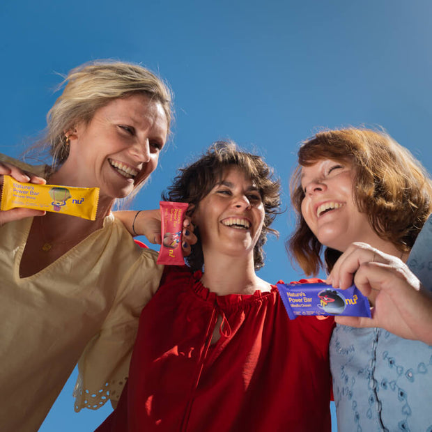 3 bunte Bars in den Händen von 3 lachenden Frauen bei blauen Himmel