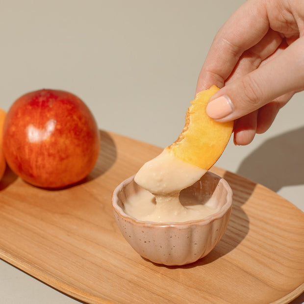 Hand dippt Obst in Nussmus-Dip