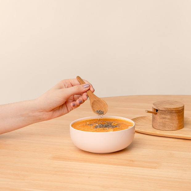 Hand hält Holzlöffel und nimmt Acerola-Dessert aus einer Bowl