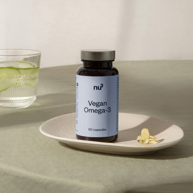 Vegan Omega 3 auf einem Teller mit zwei Kapseln auf grüner Tischdecke