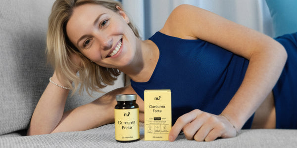 Junge Frau in blauem Top liegt auf der Couch mit dem nu3 Curcuma Forte